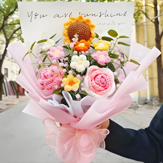 Bouquet of knitted flowers with a card reading 'You are sunshine' held outdoors.